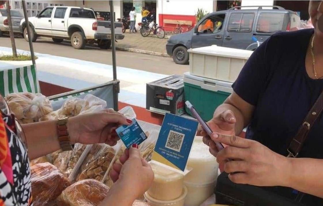 Servidora apresentando o Cartão Vale Feira em compra direta na barraca