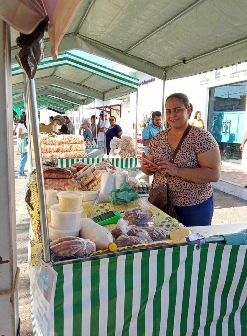 Feirante em sua barraca com pães, queijos e verduras
