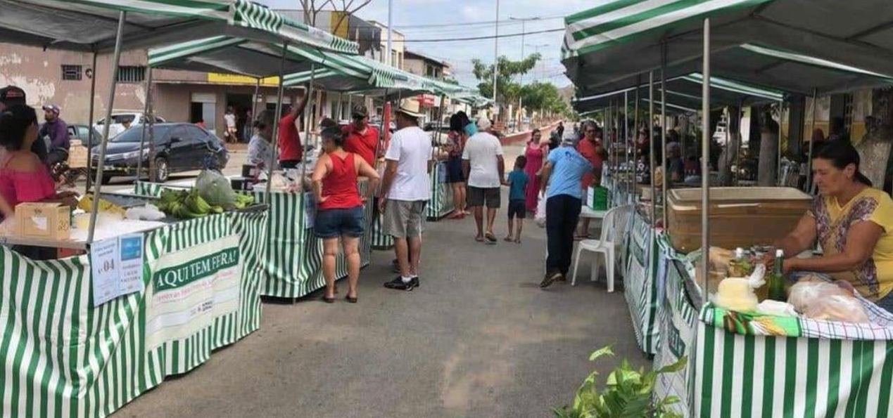 Corredor da feira com consumidores entre as barracas