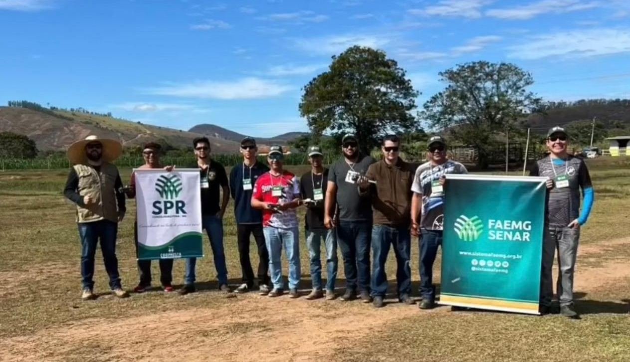 Turma do curso de drone com faixas do FAEMG SENAR no campo